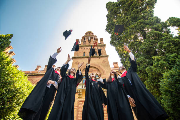 istock Successful five students with congratulations together throwing graduation hats in the air and celebrating at University. 1307598309