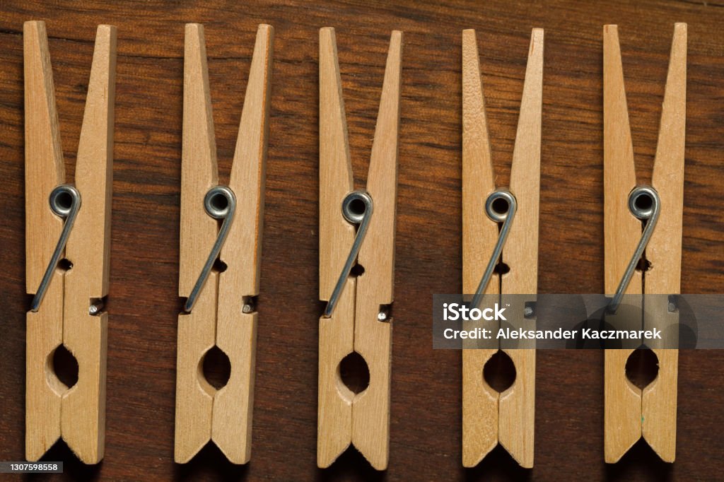 Five Wooden Clothes Pegs On A Brown Dark Table Five wooden clothes pegs lying on a dark table. Top View. Brown Stock Photo