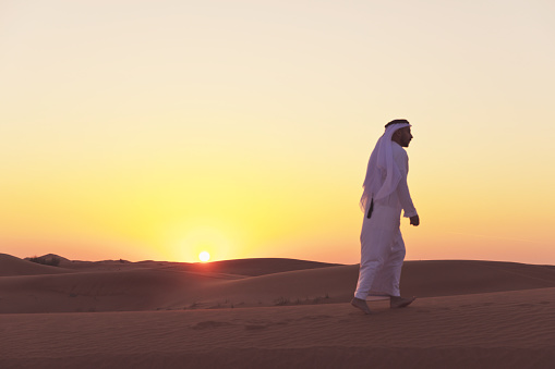 Arab man walking on the dunes of Dubai