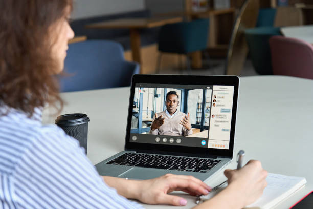 Teen girl student watching webinar, distance learning on video call with african online teacher or virtual tutor studying university seminar having online meeting on laptop screen. Over shoulder view Teen girl student watching webinar, distance learning on video call with african online teacher or virtual tutor studying university seminar having online meeting on laptop screen. Over shoulder view zoom classroom stock pictures, royalty-free photos & images