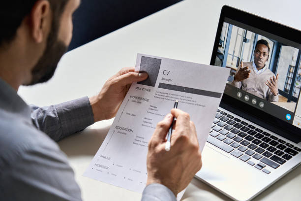 männliche indische hr, recruiter oder arbeitgeber holding cv mit online-virtual-job-interview-treffen mit afrikanischen kandidaten auf video-anruf. entfernung remote-rekrutierungskonferenz-chat. über schulter blick. - anwerber stock-fotos und bilder