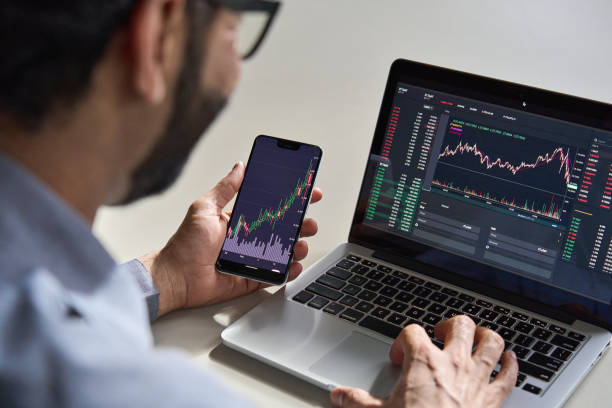 ビジネスマントレーダー投資家アナリストは、暗号通貨金融市場分析のための携帯電話アプリ分析を使用して、スマートフォンやラップトップ画面上の取引データインデックスチャートグラ� - computer monitor computer graph people ストックフォトと画像