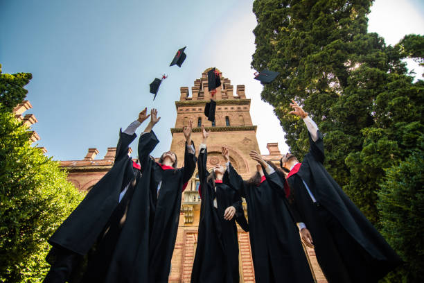 istock Successful five students with congratulations together throwing graduation hats in the air and celebrating at University. 1307599798
