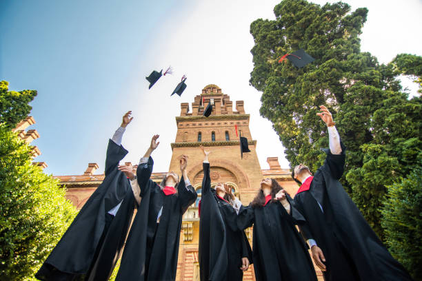 istock Graduating students throwing caps in the air at University ceremony 1307600155