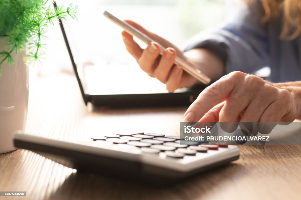 business woman hand with calculator and mobile phone Wages Stock Photo