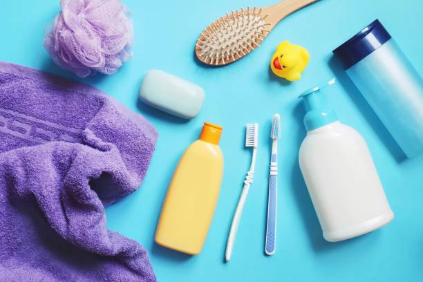 istock Flat lay composition bath products on a blue background. Purple towel, shampoo bottle, sponge, soap bar, shower gel, hair balm, comb, toothbrushes and rubber duck. Toiletries set 1307603648