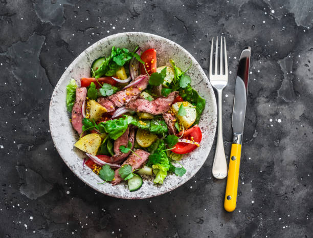 istock Potato, beef steak, romano and vegetable salad on a dark background, top view. Balanced diets healthy food 1307603933