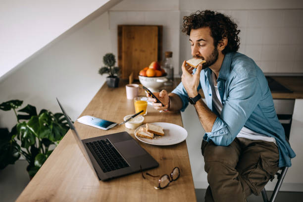 istock Young handsome casually clothed man having a online conversation while having a breakfast in his kitchen 1307605117
