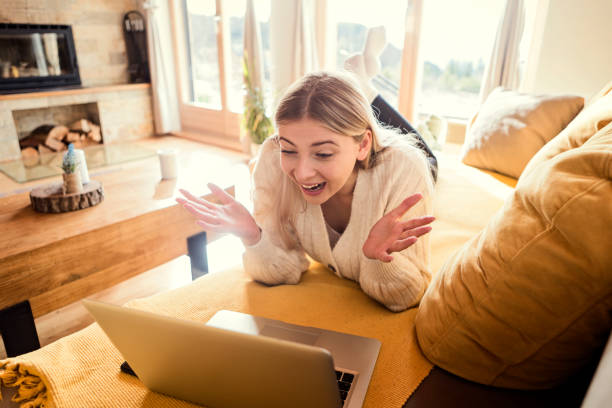 istock Waving at laptop during a video chat lying on sofa 1307605494