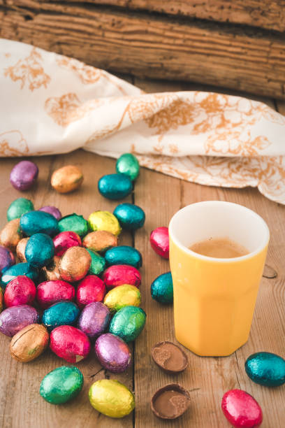 istock Cup of espresso and colorful wrapped easter chocolate eggs on a rustic wooden table, vertical 1307608555