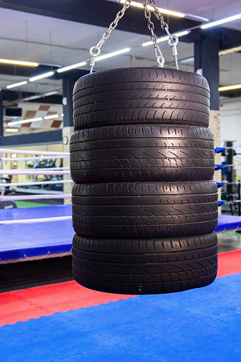 Stack of tires for punching and kicking in a gym against boxing ring background