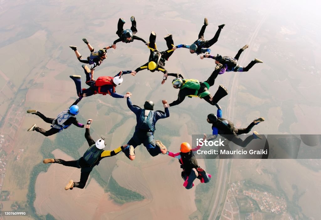 Skydive team making a formation Skydivers holding hands making a fomation. High angle view. Trust Stock Photo