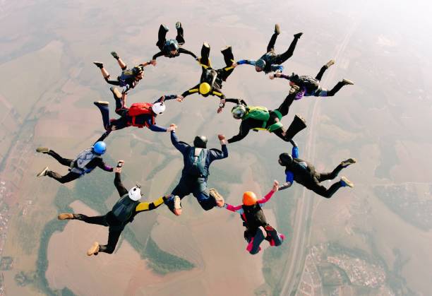 Skydive team making a formation Skydivers holding hands making a fomation. High angle view. exhilaration photos stock pictures, royalty-free photos & images