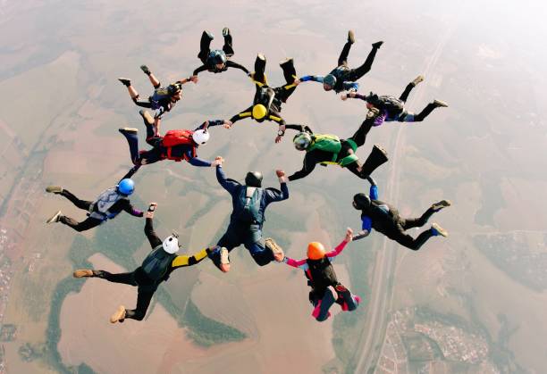 Skydive team making a formation Skydivers holding hands making a fomation. High angle view. trustees stock pictures, royalty-free photos & images