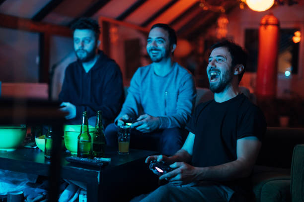 amigos gritando y animando mientras jugaban la batalla del juego en la playstation - espacio masculino fotografías e imágenes de stock