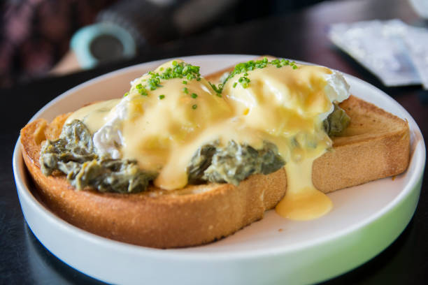 Traditional Eggs Benedict Florentine with poached eggs. creamed spinach, green onions, Hollandaise sauce and nutmeg, over a brioch bread stock photo