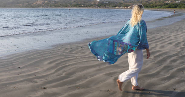 istock Woman walks down sandy beach at sunrise 1307612404