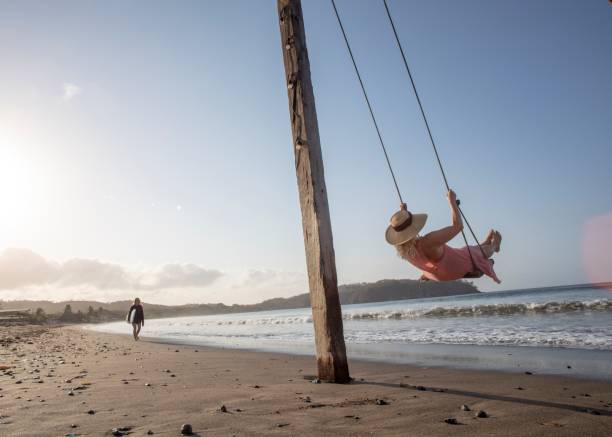 istock Woman enjoys waterfront swing on beach at sunrise 1307612484