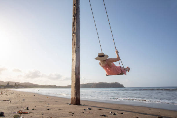 istock Woman enjoys waterfront swing on beach at sunrise 1307612504