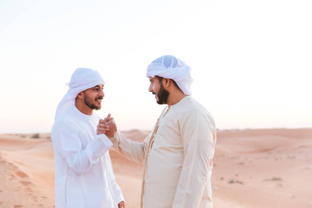 악수를 통해 형제애를 보여주는 아랍 남자 - desert men mid adult men looking at camera 뉴스 사진 이미지