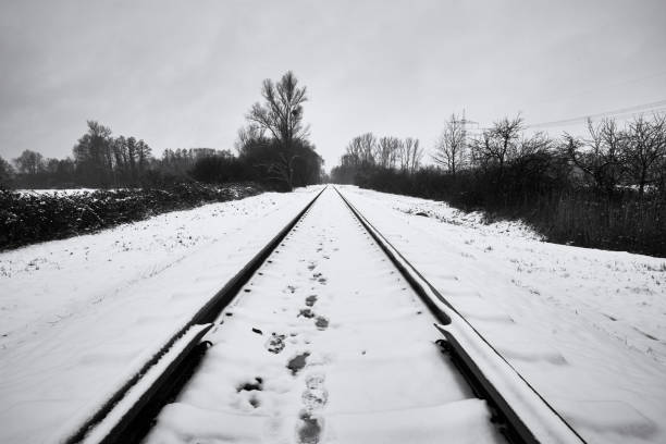 Footprints in the snow on old railroad track in winter, black and white. Rastatt, Germany.