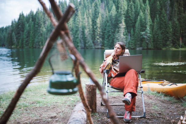 istock Young beautiful woman using her laptop for work, while camping in the nature. 1307616249