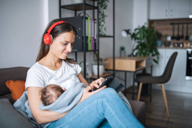 Young mother relaxing at home while holding her sleeping baby.