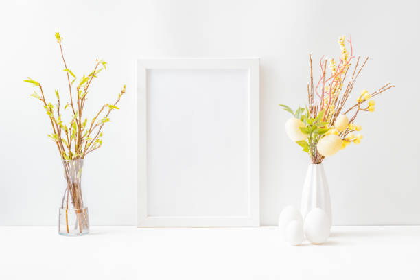 istock Home interior with easter decor. Mockup with a white frame and willow branches in a vase on a light background 1307616975