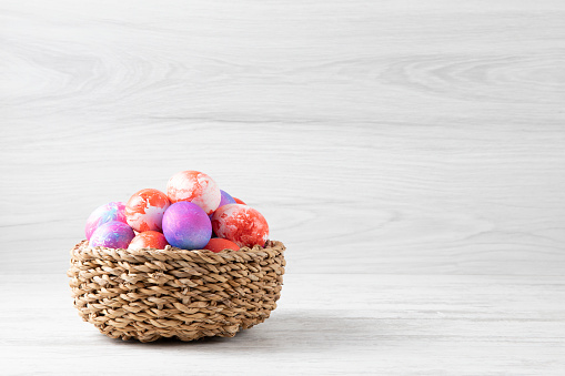 Tie dyed Easter eggs on white rustic background.