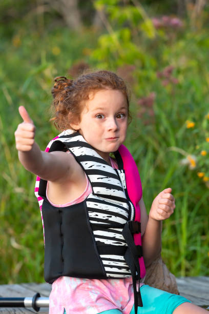 istock Girl Sitting on Dock Giving Thumbs Up 1307619469
