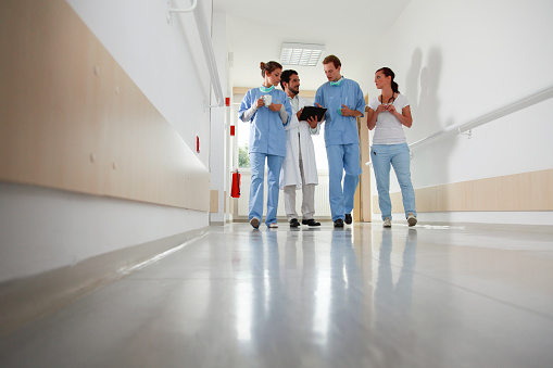Doctor teache and medical students in a corridor after their rounds discussing cases.