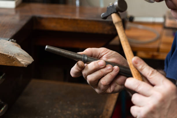 istock foreground, hammer hammering a silver ring to shape it in a jewelry workshop. 1307622387