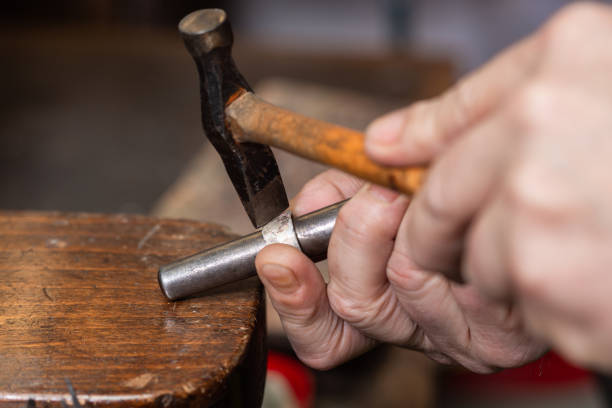 istock foreground, hammer hammering a silver ring to shape it in a jewelry workshop. 1307623061