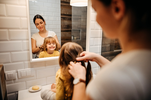Young mother combing hair to her daughter