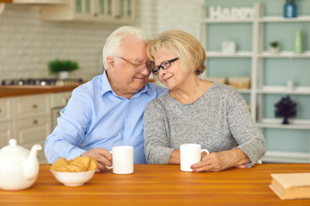 istock Happy senior couple drinking tea and hugging each other sitting at table in the kitchen 1307625169