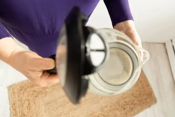 Photo of woman hands kettle with Limescale. chalky residue of calcium carbonate. Household appliances repair caused by hard water