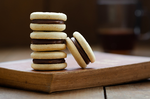 Cornstarch alfajores stack on an old brown book and a cup of tea.