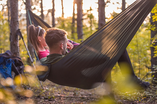 Boy and girl camping in forest, laying in hammock