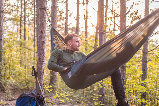 Boy camping in forest, laying in hammock