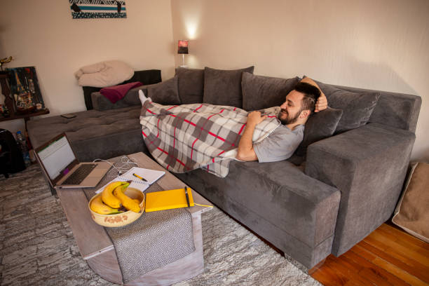istock Young man laying on a sofa and having a video call on laptop 1307628539