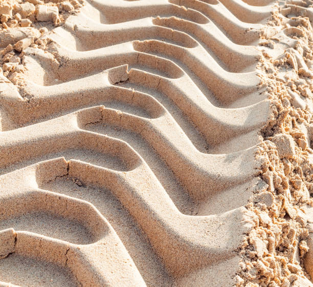 A close-up showing freshly laid tire tracks in sand.