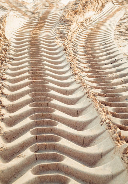 Industrial tire track marks in sand, seen in perspective.