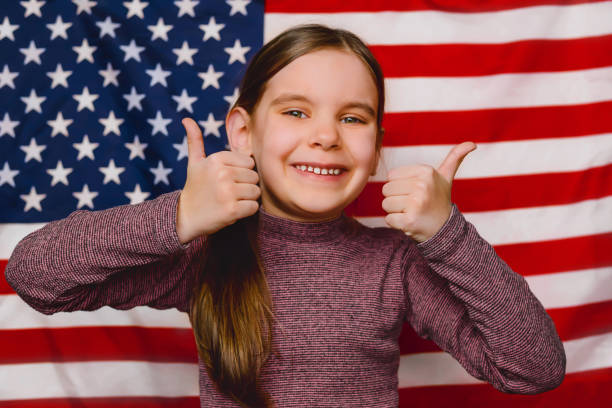 menina criança feliz e fundo da bandeira americana. expressão de patriotismo e amor por seu país, os estados unidos. - child flag patriotism thumbs up - fotografias e filmes do acervo