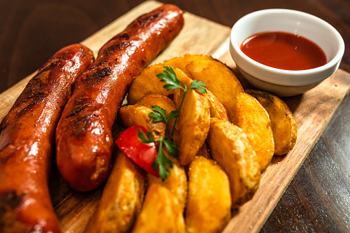 Sausages and roasted potato served on wooden board