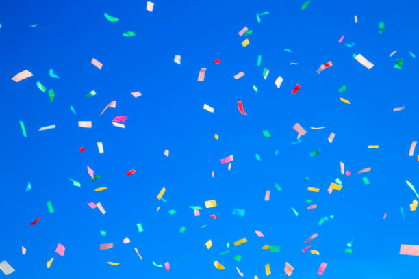 istock multicolored confetti on clear blue sky background. Concept of h 1307636659