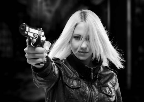 Portrait of a young woman with a pistol. It is the moment of deciding. She has just jerked the gun up. Dark and mysterious, Film Noir style.