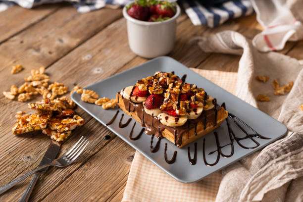 Waffle with strawberries, walnuts, bananas and chestnuts with chocolate sauce.