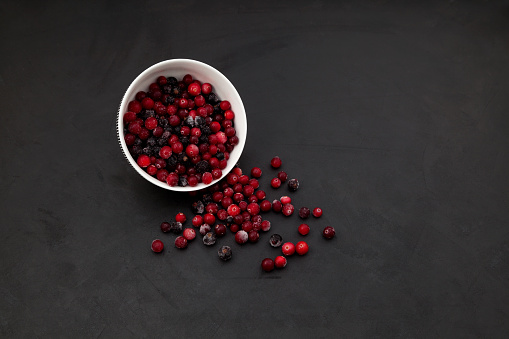 Frozen cranberry on dark background with copy space. Natural source of vitamin C, an ingredient for healthy smoothies or fruit drinks.
