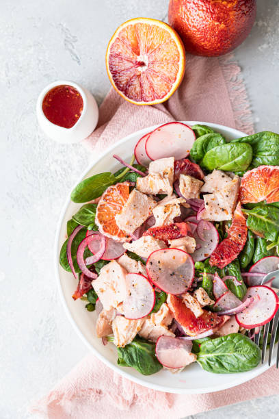 istock Fresh salad with salmon, spinach, radish and red oranges served with orange sauce, light concrete background. Top view. 1307639771