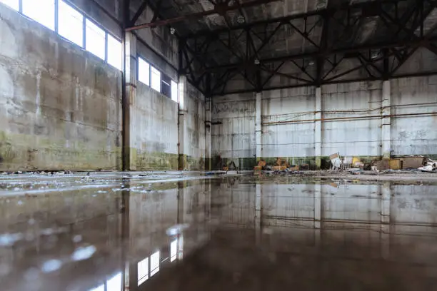 Photo of Inside of flooded dirty abandoned ruined industrial building with water reflection